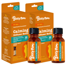 Two amber bottles with black caps labeled "Zesty Paws Calming Diffuser Refill" next to orange product packaging boxes.